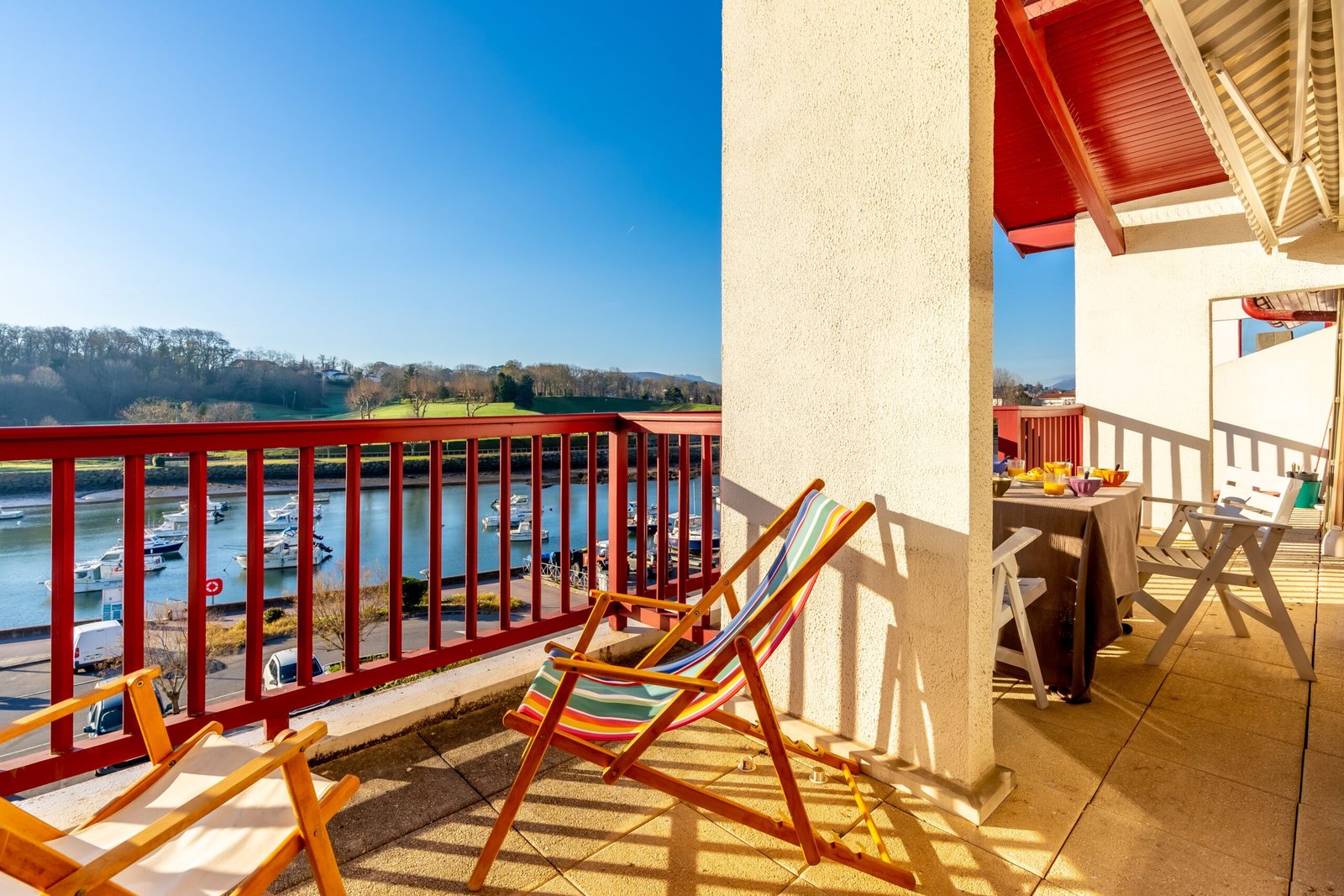 The chairs with a matching table situated on a balcony overlooking a tranquil seascape